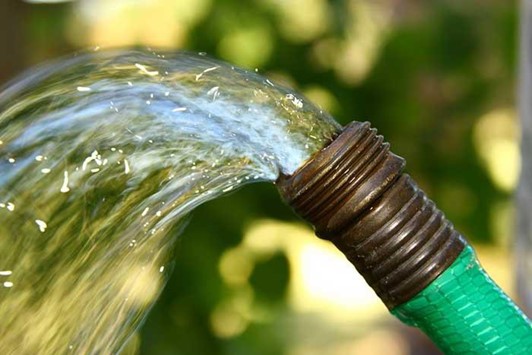 photo of water coming from a garden hose to illustrate water usage or restrictions